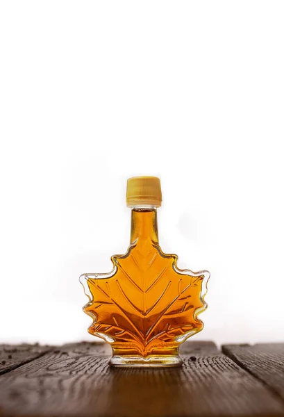Sirup Maple dalam botol kaca di atas meja kayu dengan latar belakang putih Stok Gambar Bebas Royalti