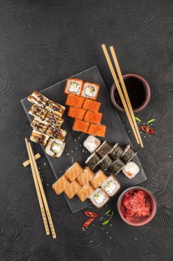 Karanlık bir arka planda Japon suşisi. Suşi, nigiri, maki, zencefil turşusu, wasabi, soya sosu. Kopyalama alanı ile üst görünüm. Asya ya da Japon mutfağı.