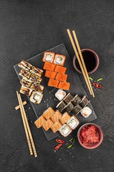 Japanese sushi on a dark background. Sushi rolls, nigiri, maki, pickled ginger, wasabi, soy sauce. Top view with copyspace. Asian or Japanese cuisine.