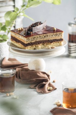 Tahta tezgahta fındıklı çikolatalı pasta, çaydanlık ve arka planda bir fincan çay. Metin için bir kopya alanı ile yan görünüm. Tatillerde yemek için tatlı. Dikey yönelim.