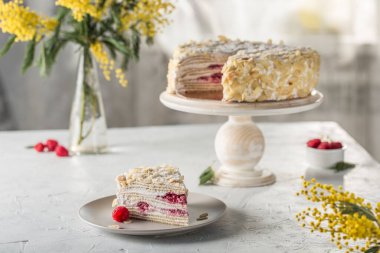Napolyon puf keki. Tahta tezgahın üzerinde böğürtlen dolgulu. Tabakta da kesik bir parça var. Evin arka planında, metin için bir kopya alanı olan bir kenar görünüm. Rus doğum günü pastası.