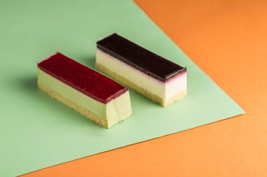 Çok renkli arka planda farklı kremalı iki kremalı kek. Metin için bir kopya alanı ile yan görünüm. Tatil ve doğum günü için tatlı. Yatay yönelim.