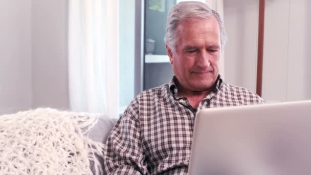 Handsome mature man using laptop on the couch — Stock Video