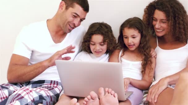 Linda familia usando ordenador portátil en su cama — Vídeos de Stock