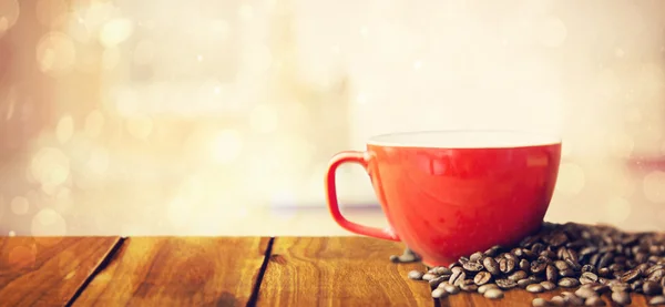 Houten tafel tegen koffiebonen en cup — Stockfoto