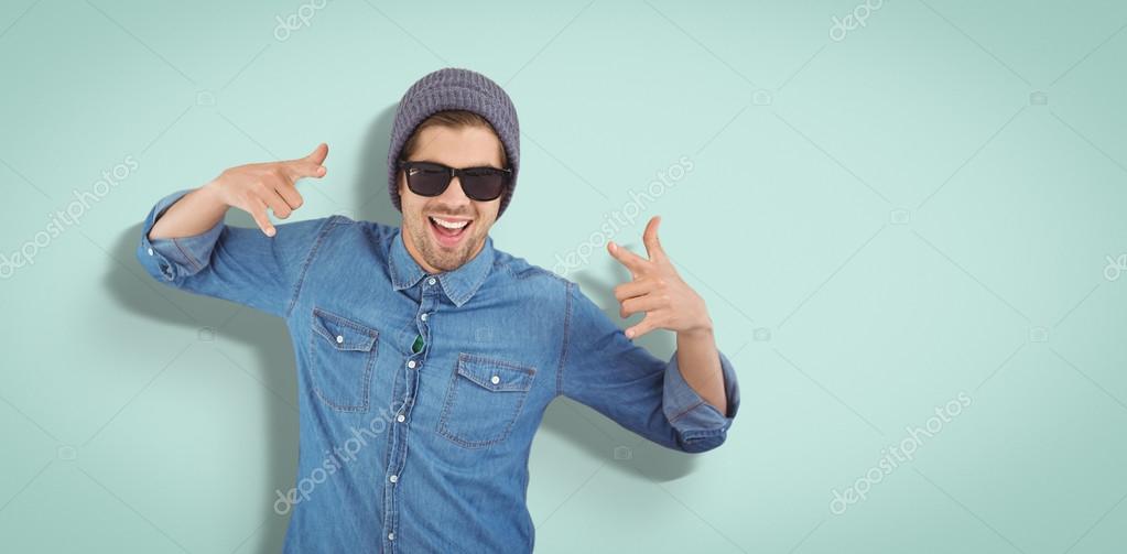 Happy hipster showing rock and roll hand sign against blue vignette background
