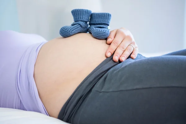 Mulher grávida com sapatos de bebê na barriga — Fotografia de Stock