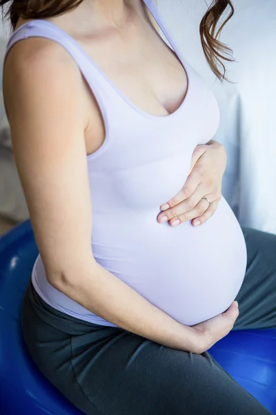 怀孕的女人坐在健身球上 — 图库照片