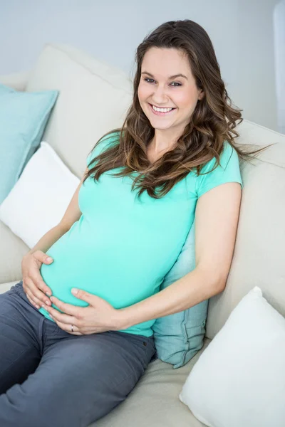 Femme enceinte assise sur le canapé — Photo