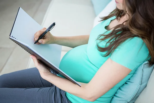 Pregnant woman writing on document — Stock Photo, Image