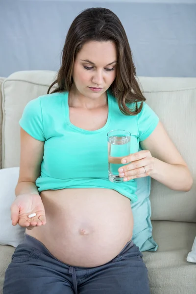 Kobieta w ciąży trzymając szklankę wody i tabletki — Zdjęcie stockowe