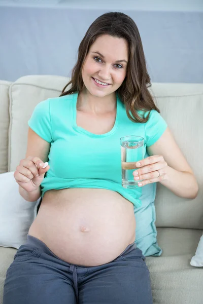 Mujer embarazada sosteniendo un vaso de agua y pastillas —  Fotos de Stock