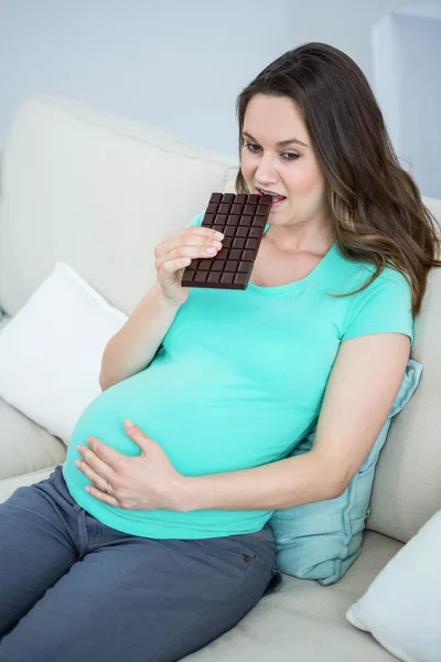 Smiling pregnant woman eating chocolate — Stock Photo, Image