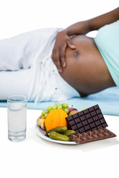 Έγκυος γυναίκα ξαπλωμένη από φρούτα και σοκολάτες — Φωτογραφία Αρχείου