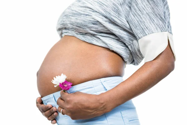Беременная женщина с цветком трогает живот — стоковое фото
