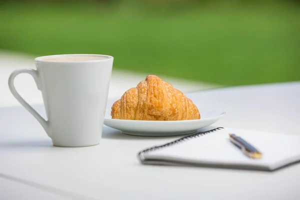 Carnet avec stylo et café par la nourriture — Photo