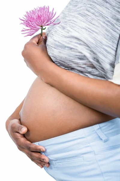 妊娠中の女性と彼女の腹に触れる花 — ストック写真