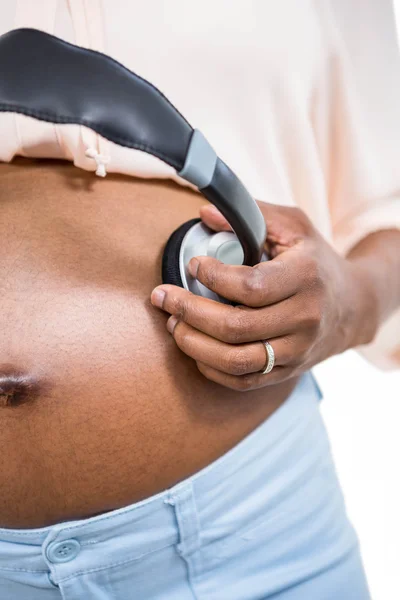 Donna incinta che tiene le cuffie sulla pancia — Foto Stock