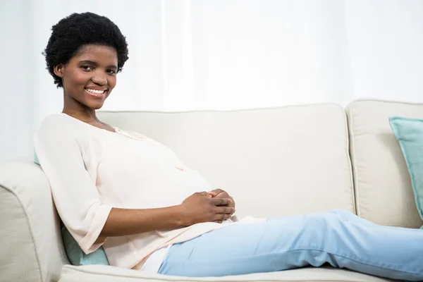 Těhotná žena uvolňující na gauči — Stock fotografie
