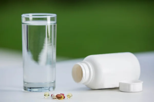 Pastillas junto a vaso de agua — Foto de Stock