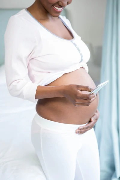 Беременная женщина с помощью смартфона — стоковое фото