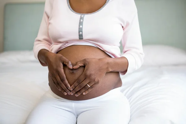 Mujer embarazada haciendo forma de corazón —  Fotos de Stock