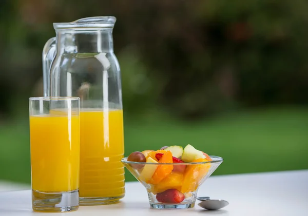 Tigela de salada de frutas com suco de laranja — Fotografia de Stock