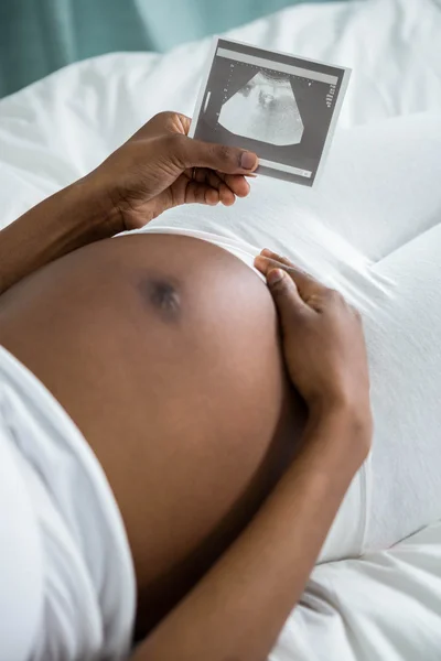 Pregnant woman looking at ultrasound pictures — Stock Photo, Image