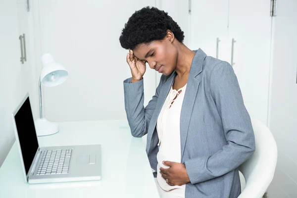 Embarazada mujer de negocios tocándose la cabeza y el vientre —  Fotos de Stock