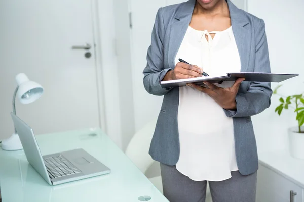 Schwangere Geschäftsfrau schreibt auf Notizbuch — Stockfoto