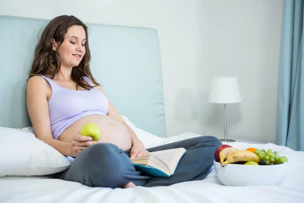 Mujer embarazada leyendo un libro — Foto de Stock
