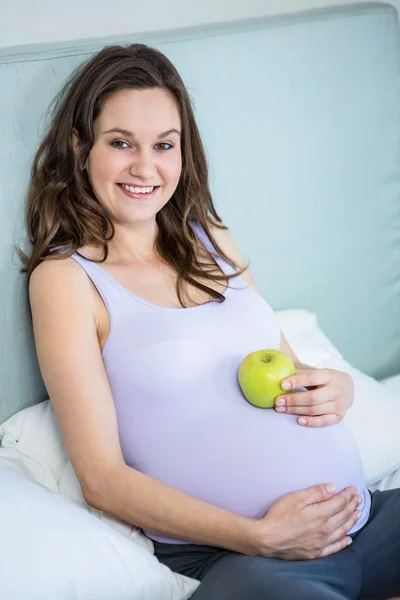 Mujer embarazada sosteniendo una manzana en su bulto —  Fotos de Stock