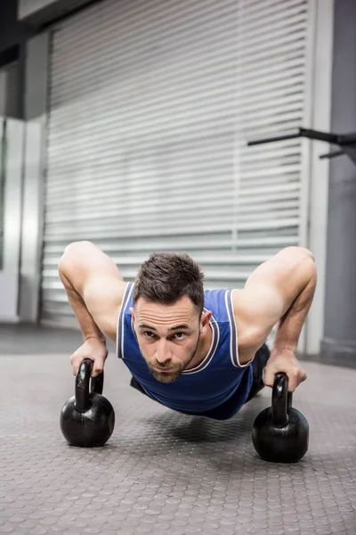 Muskulöser Mann macht Liegestütze mit Kettlebells — Stockfoto