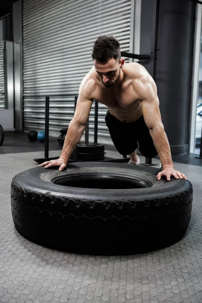 Shirtless chlap obracející těžké pneumatiky — Stock fotografie