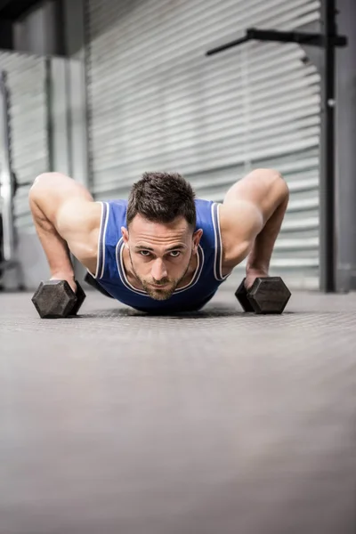 Musculoso hombre haciendo empujar hacia arriba con mancuernas —  Fotos de Stock