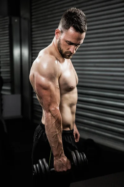 Shirtless man holding heavy dumbbell — Stock Photo, Image