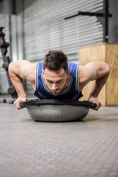 Gespierde man doet duw omhoog op bosu bal — Stockfoto