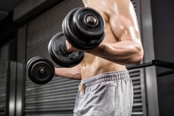 Mid section of shirtless man lifting heavy dumbbells — Stock Photo, Image