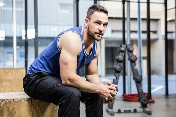 Homme musclé assis sur un bloc de bois — Photo