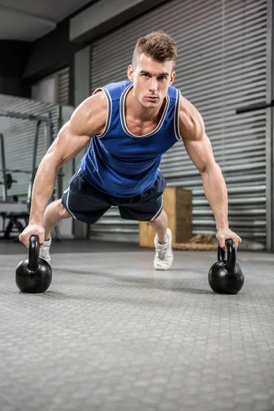 Musculoso hombre haciendo push up con kettlebells — Foto de Stock