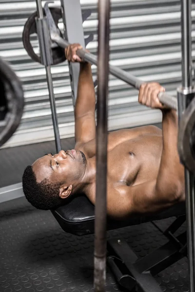 Homem sem camisa levantando barbell no banco — Fotografia de Stock