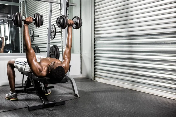 Shirtless man lifting dumbbells on bench — Stock Photo, Image