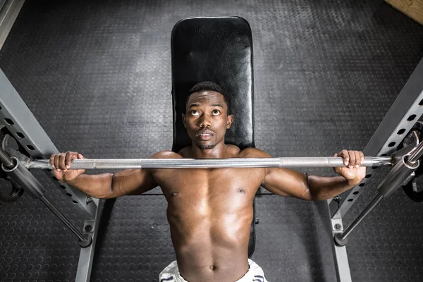 Homem sem camisa levantando barbell no banco — Fotografia de Stock