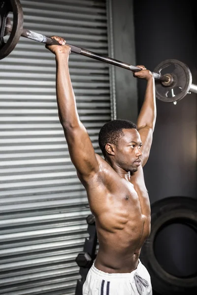 Homem sem camisa levantando barbell — Fotografia de Stock