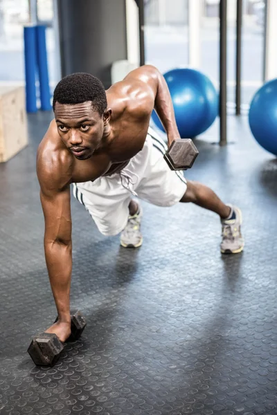 Musculoso hombre haciendo empujar hacia arriba con mancuernas — Foto de Stock