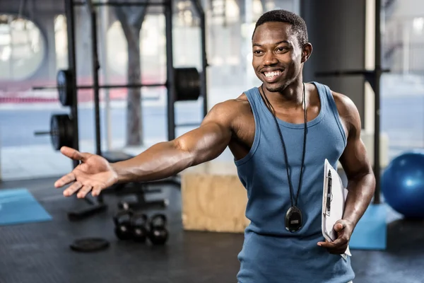 Vertrouwen trainer tonen de sportschool naar de camera — Stockfoto