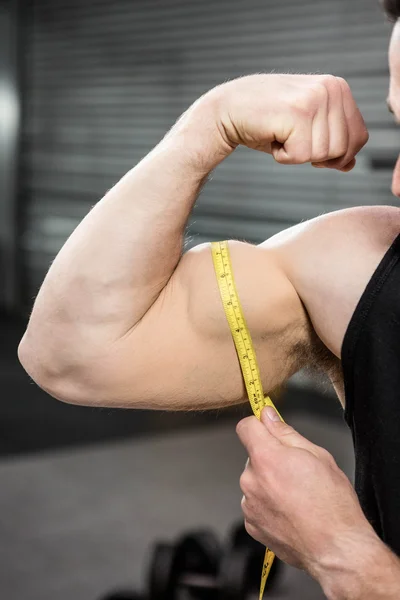 Muscular man measuring biceps — Stock Photo, Image