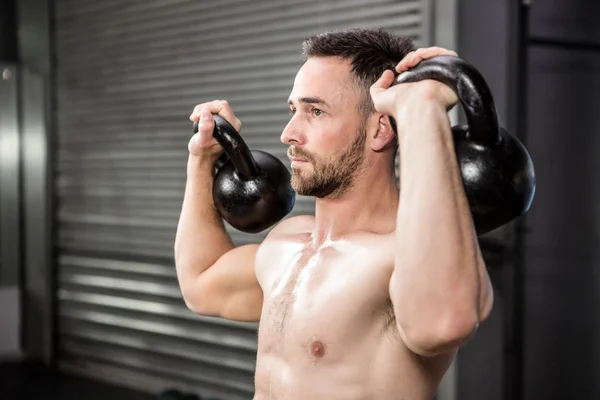 Homem sem camisa levantando kettlebells — Fotografia de Stock