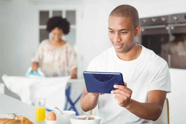 Hombre joven usando la tableta en la cocina — Foto de Stock