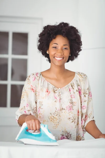 Smiling woman ironing in the kitchen — Stockfoto